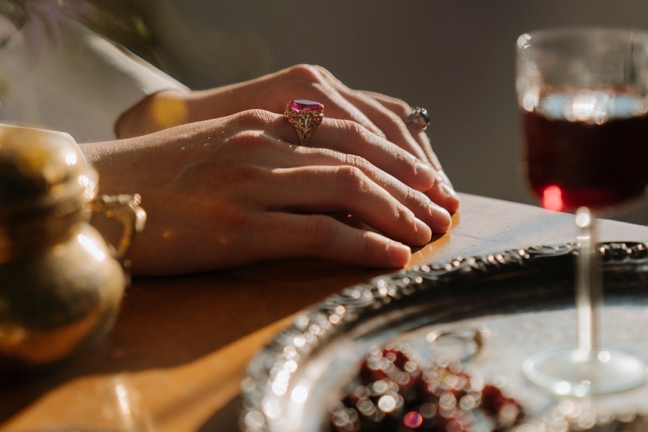 a lady’s hands resting on a table and wearing fashion rings