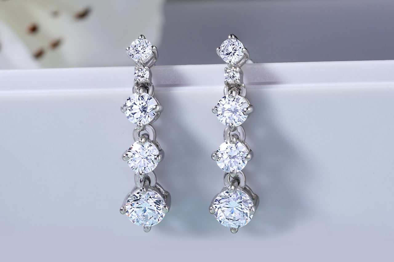 A pair of silver, four-tiered diamond earrings featuring round-cut diamonds A pair of silver, four-tiered diamond earrings featuring round-cut diamonds