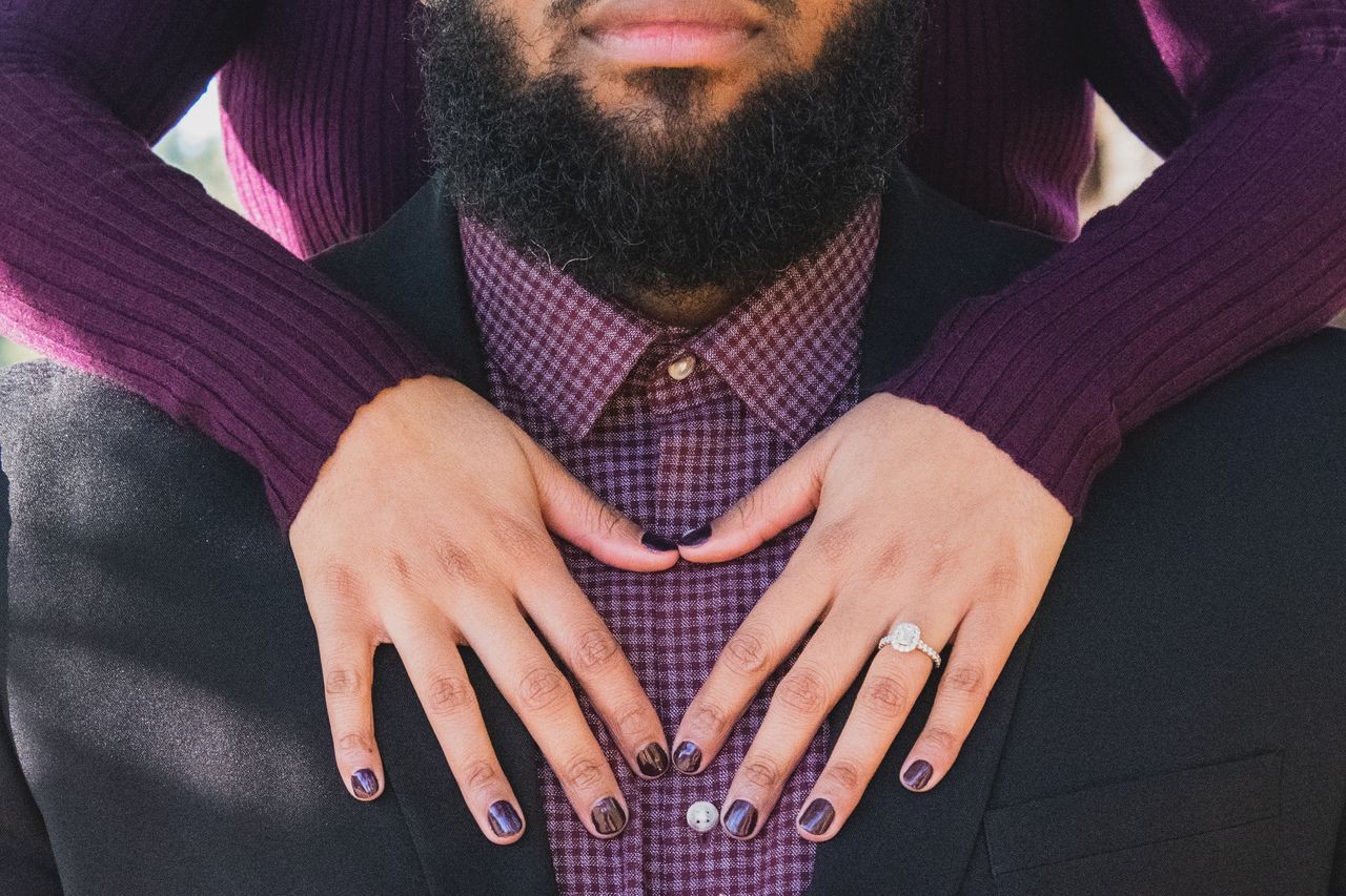 A woman places her hands on man's chest, showing off here halo engagement ring A woman places her hands on man's chest, showing off here halo engagement ring