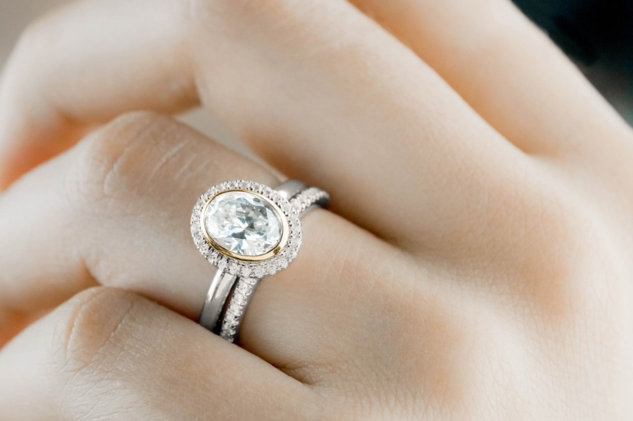 Close up image of a hand wearing a silver and gold engagement ring and diamond wedding band Close up image of a hand wearing a silver and gold engagement ring and diamond wedding band