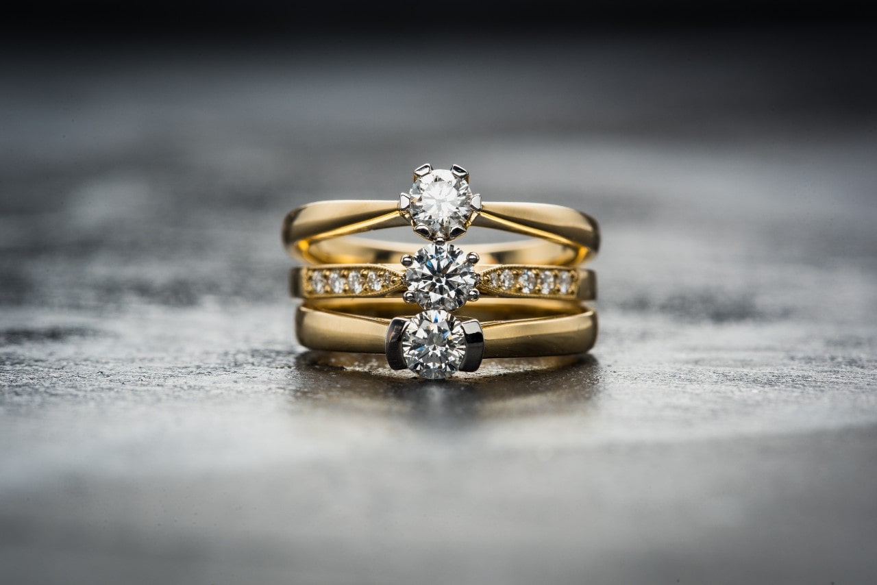 A trio of round cut rings sitting on top of each other against a grey backdrop A trio of round cut rings sitting on top of each other against a grey backdrop