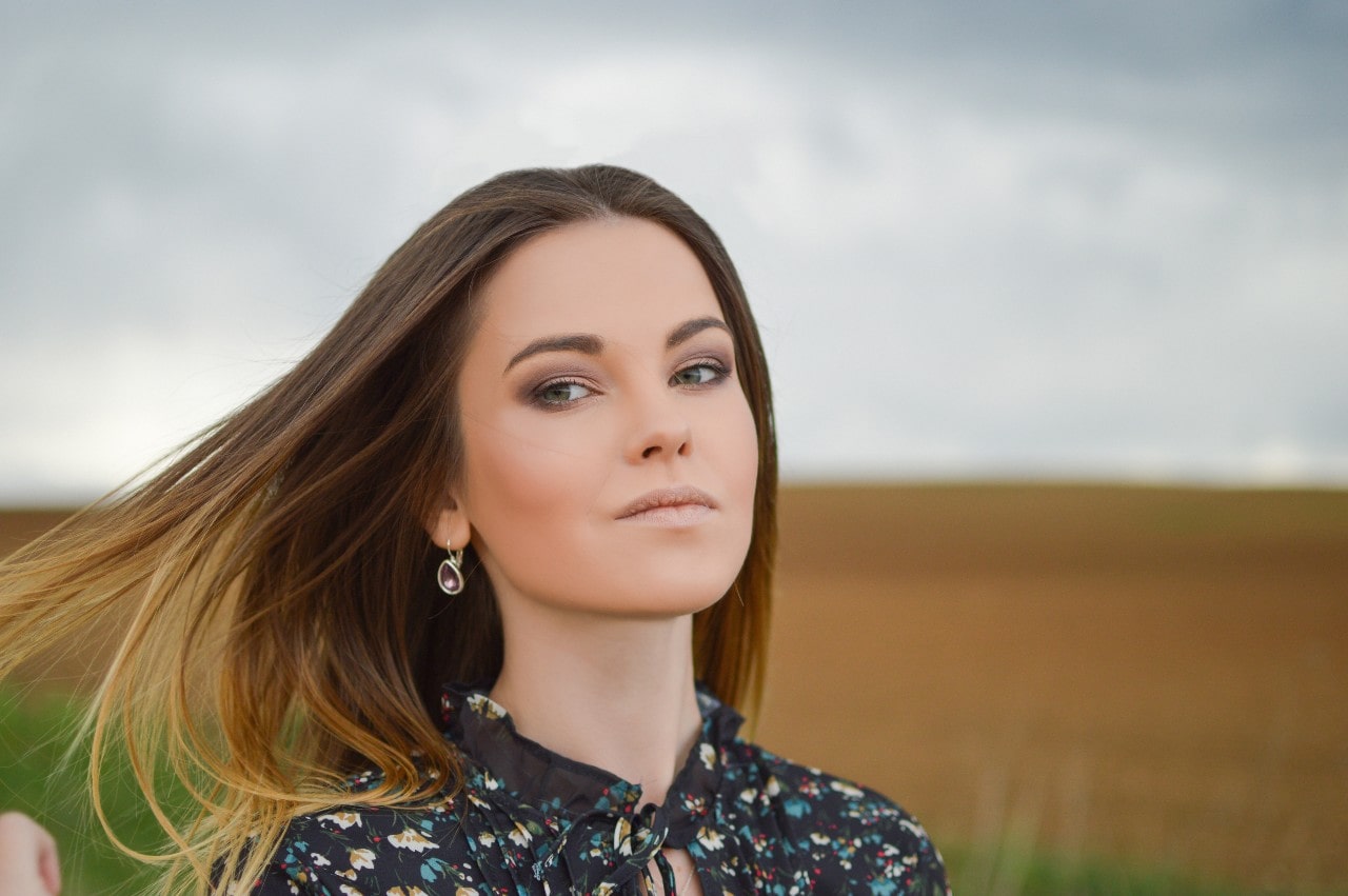 A woman in a floral blouse wears TACORI gemstone drop earrings A woman in a floral blouse wears TACORI gemstone drop earrings