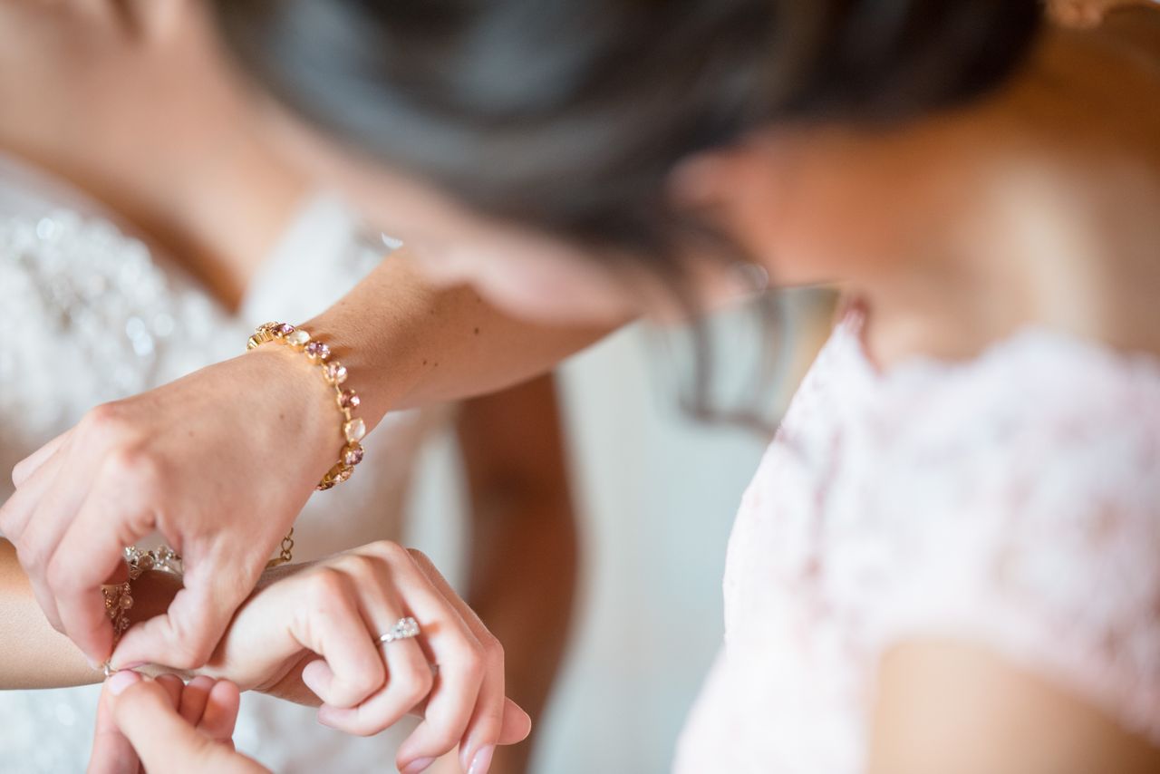 A woman wearing a gemstone bracelet fastens her friend's bracelet A woman wearing a gemstone bracelet fastens her friend's bracelet