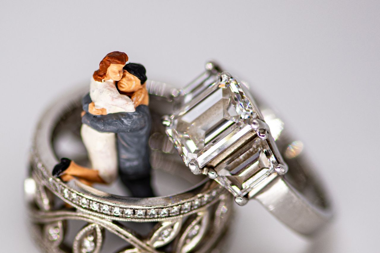 A wedding cake topper sits with a wedding band and engagement ring from TACORI A wedding cake topper sits with a wedding band and engagement ring from TACORI